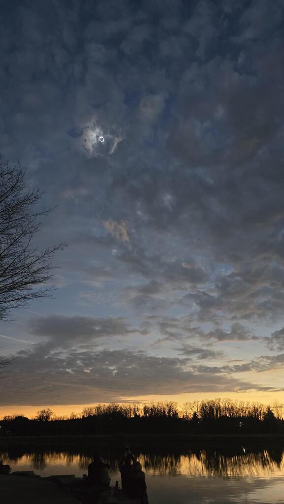 Photo of a total solar eclipse with sunset sky background.